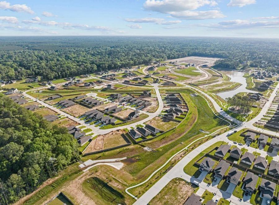 Aerial view of a new single-family subdivision under construction beside a pond and pine forest